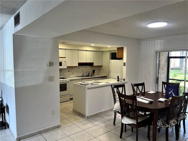 kitchen featuring light tile patterned flooring, white appliances, and a textured ceiling