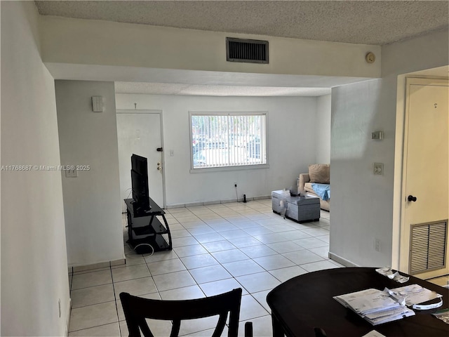living area featuring baseboards, a textured ceiling, visible vents, and light tile patterned floors