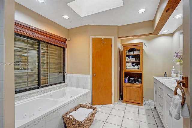 bathroom with vanity, a tub with jets, a skylight, recessed lighting, and tile patterned floors