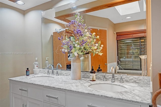 full bathroom with double vanity, recessed lighting, a skylight, and a sink