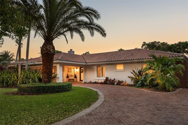13453 SW 58th Ave, Pinecrest, FL 33156 - view of front of property featuring stucco siding, a tiled roof, curved driveway, and a front yard