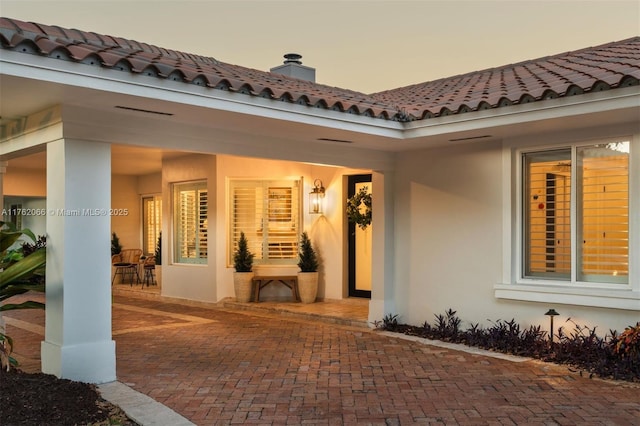13453 SW 58th Ave, Pinecrest, FL 33156 - exterior entry at dusk featuring stucco siding, a tile roof, and a chimney