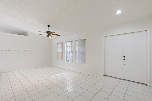unfurnished room with light tile patterned floors, a textured ceiling, a ceiling fan, and vaulted ceiling