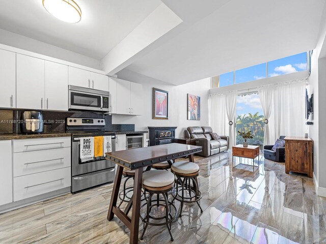 820 NW 87th Ave Unit 409, Miami, FL 33172 - kitchen with beamed ceiling, backsplash, wine cooler, appliances with stainless steel finishes, and white cabinets