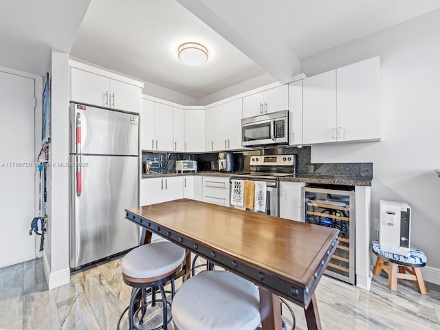 820 NW 87th Ave Unit 409, Miami, FL 33172 - kitchen featuring wine cooler, appliances with stainless steel finishes, white cabinetry, dark countertops, and tasteful backsplash