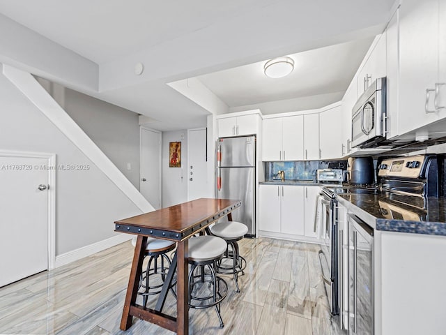 820 NW 87th Ave Unit 409, Miami, FL 33172 - kitchen featuring light wood-style flooring, stainless steel appliances, white cabinetry, dark countertops, and tasteful backsplash