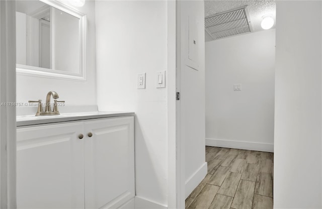 bathroom with baseboards, visible vents, wood finished floors, and vanity