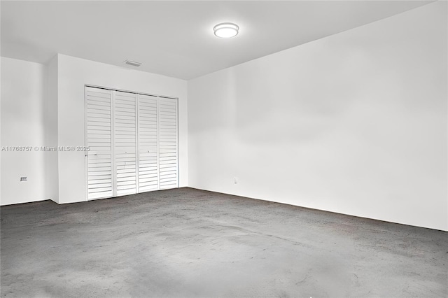 unfurnished bedroom featuring concrete floors, a closet, and visible vents