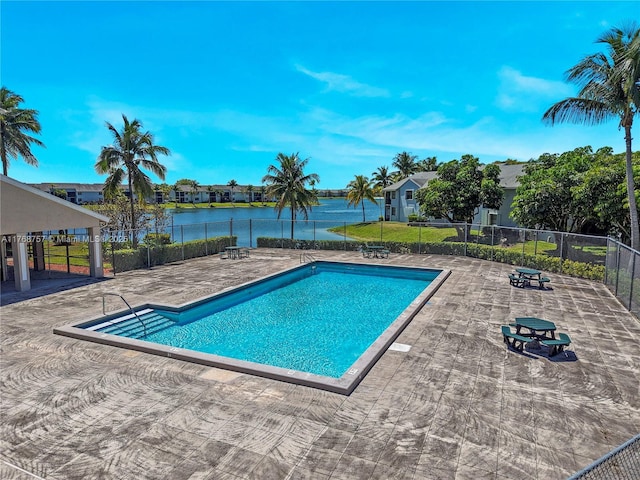 community pool featuring fence, a patio area, and a water view