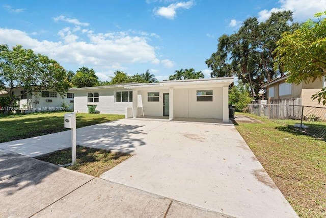 ranch-style home with a front lawn, stucco siding, fence, and concrete driveway