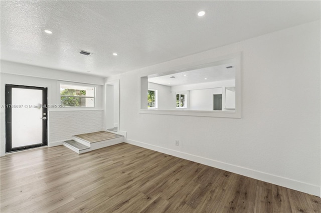 empty room featuring recessed lighting, baseboards, a textured ceiling, visible vents, and wood finished floors
