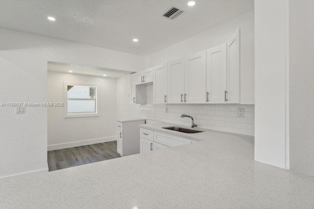 kitchen featuring a sink, visible vents, white cabinets, decorative backsplash, and recessed lighting