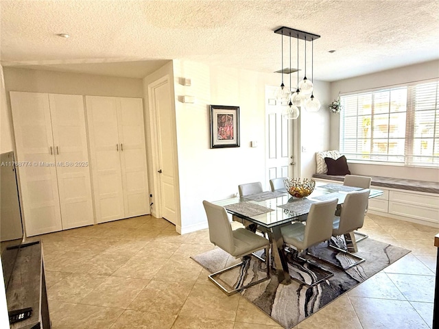 dining space with light tile patterned floors, a textured ceiling, and baseboards