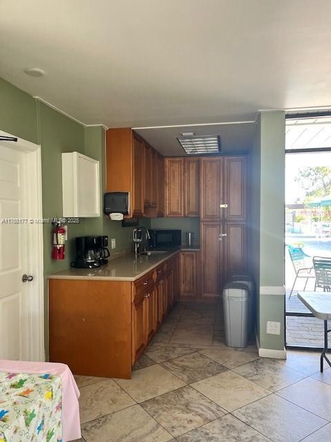 410 SW Natura Ave, Deerfield Beach, FL 33441 - kitchen featuring a sink, black microwave, brown cabinetry, and light countertops