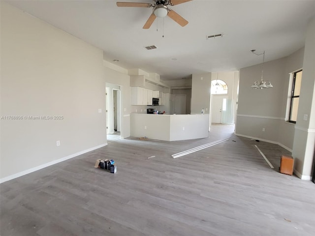 4904 Yellowstone Dr, New Port Richey, FL 34655 - unfurnished living room featuring ceiling fan, a chandelier, light wood finished floors, and baseboards
