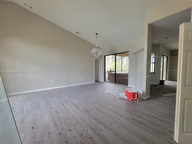 4904 Yellowstone Dr, New Port Richey, FL 34655 - unfurnished living room featuring vaulted ceiling, wood finished floors, baseboards, and a chandelier