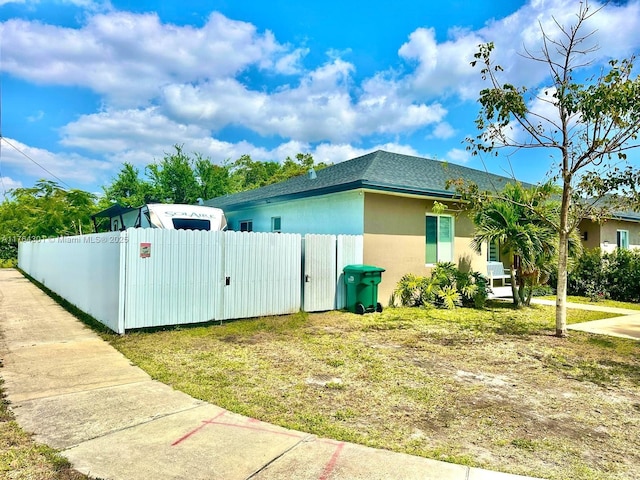 2075 NW 75th St, Miami, FL 33147 - view of property exterior with a gate, a fenced front yard, stucco siding, and a shingled roof
