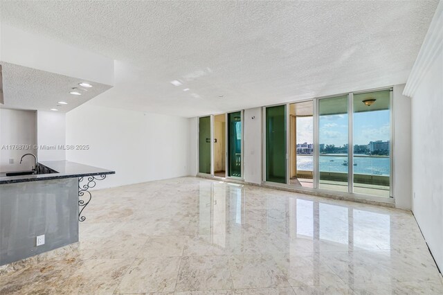 550 SE 5th Ave Unit 606S, Boca Raton, FL 33432 - unfurnished living room featuring a textured ceiling, floor to ceiling windows, a sink, and a water view
