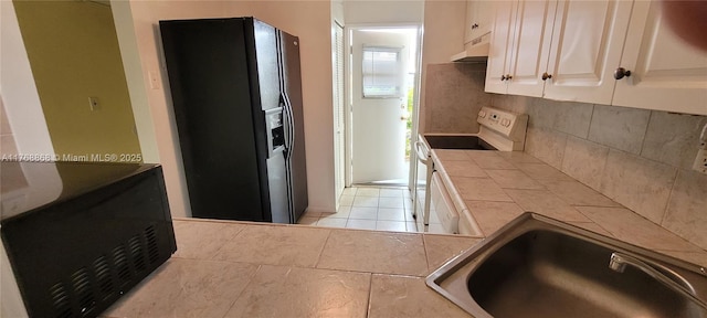 kitchen with electric stove, a sink, under cabinet range hood, tile counters, and black refrigerator with ice dispenser