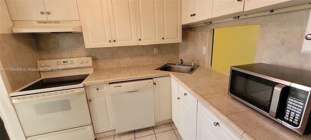 kitchen with under cabinet range hood, a sink, white appliances, white cabinets, and light countertops
