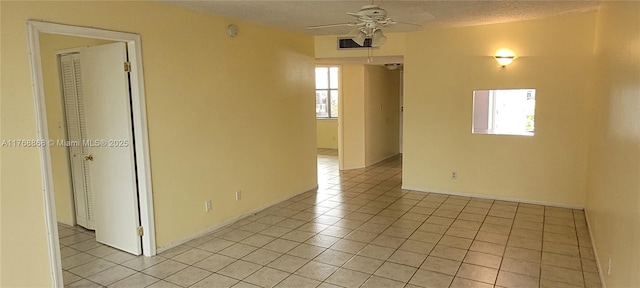 empty room with a textured ceiling, ceiling fan, and light tile patterned flooring