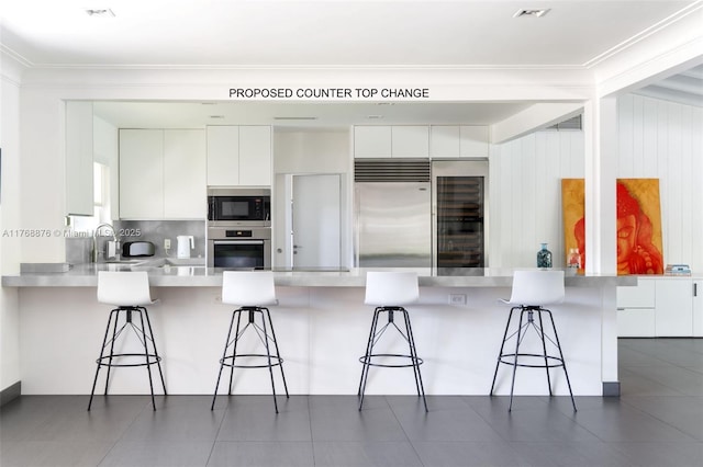 kitchen featuring light countertops, white cabinets, modern cabinets, and built in appliances