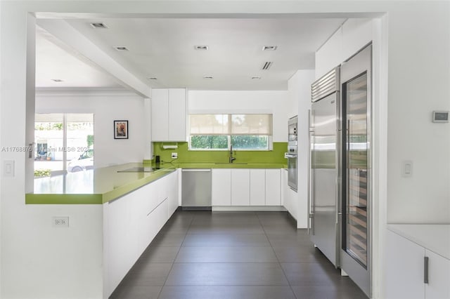 kitchen with stainless steel appliances, a sink, white cabinets, a peninsula, and modern cabinets