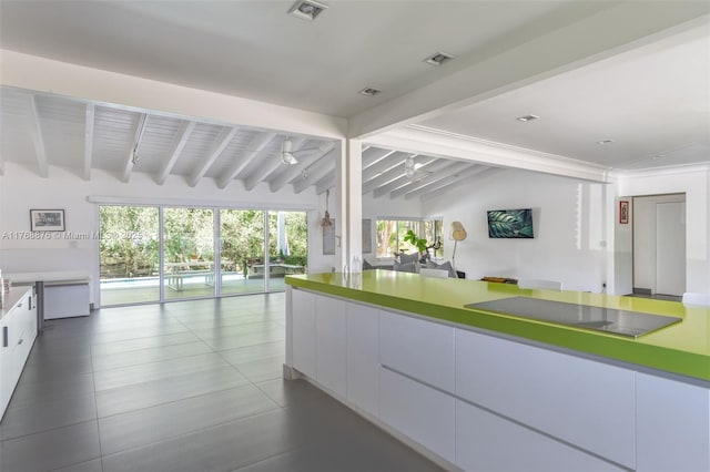 kitchen with plenty of natural light, modern cabinets, white cabinetry, open floor plan, and vaulted ceiling with beams