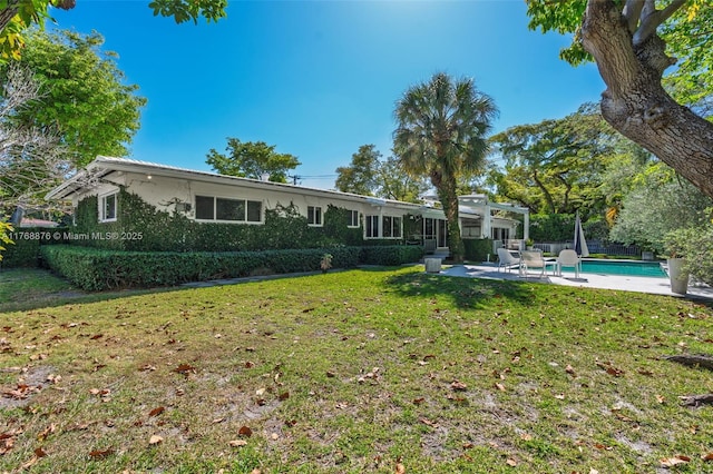 rear view of house featuring a lawn, a patio area, and a fenced in pool