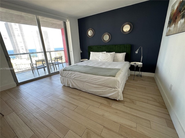 2600 E Hallandale Beach Blvd Unit T2202, Hallandale Beach, FL 33009 - bedroom with an accent wall, a wall of windows, baseboards, light wood-style floors, and access to outside