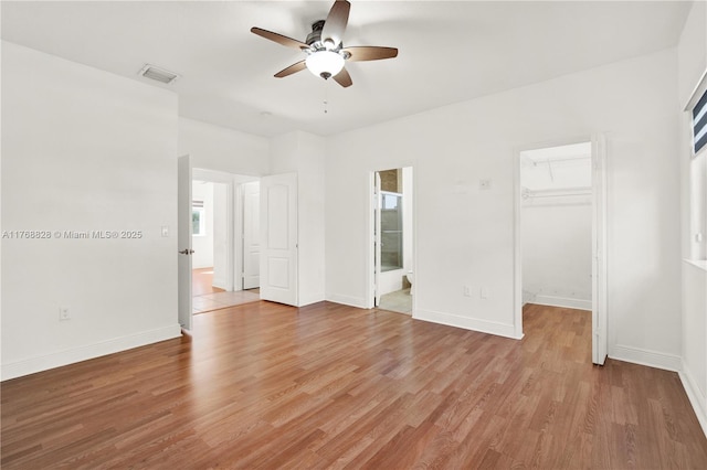 unfurnished bedroom featuring light wood finished floors, visible vents, baseboards, and a spacious closet
