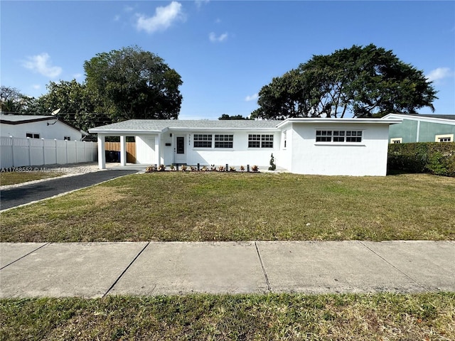 ranch-style house with fence, stucco siding, a front lawn, driveway, and a carport
