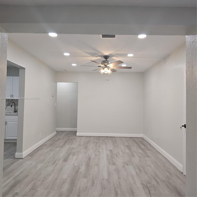 empty room featuring light wood finished floors, baseboards, ceiling fan, recessed lighting, and a sink