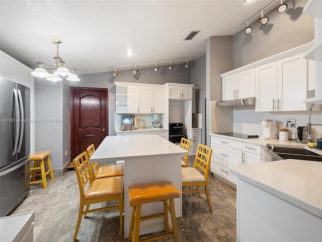 kitchen with track lighting, visible vents, a sink, freestanding refrigerator, and a chandelier
