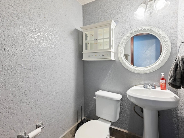 half bath featuring toilet and a textured wall