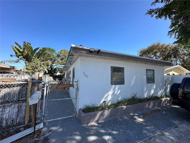 view of side of property featuring stucco siding, fence, and a gate