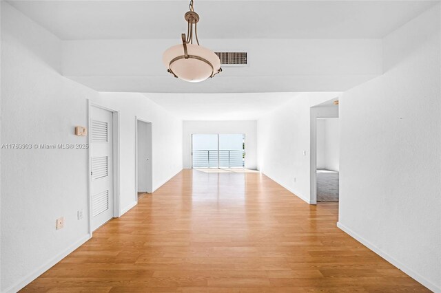 empty room featuring baseboards, light wood-style floors, and visible vents