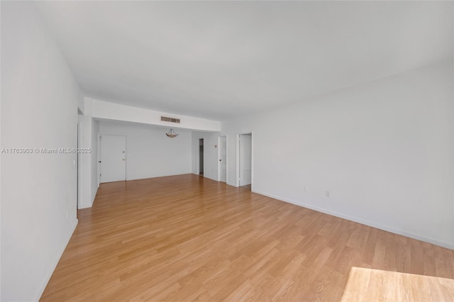 empty room with light wood-style floors and visible vents