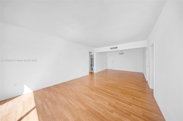 empty room with baseboards, light wood-style floors, and visible vents