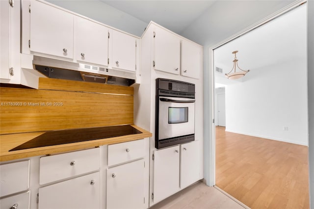 kitchen featuring white cabinets, oven, light countertops, visible vents, and light wood-style floors