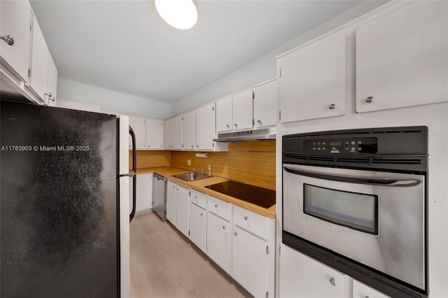 kitchen with white cabinets, under cabinet range hood, light countertops, a sink, and appliances with stainless steel finishes