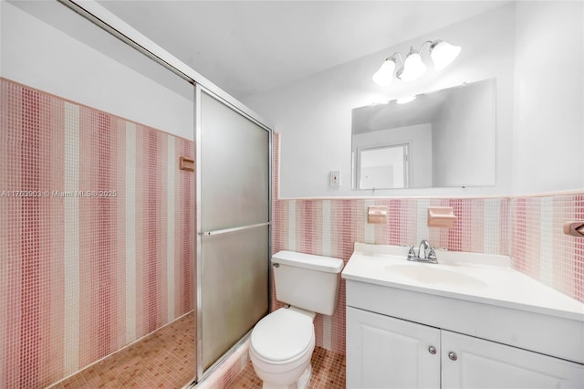 full bath with a shower stall, vanity, toilet, and tile walls