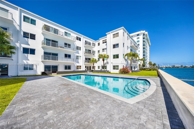pool featuring a patio area and a water view