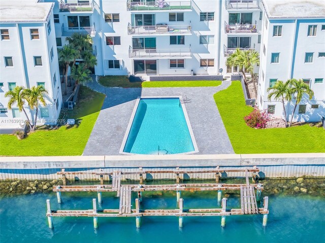 view of swimming pool featuring boat lift, a boat dock, and a water view