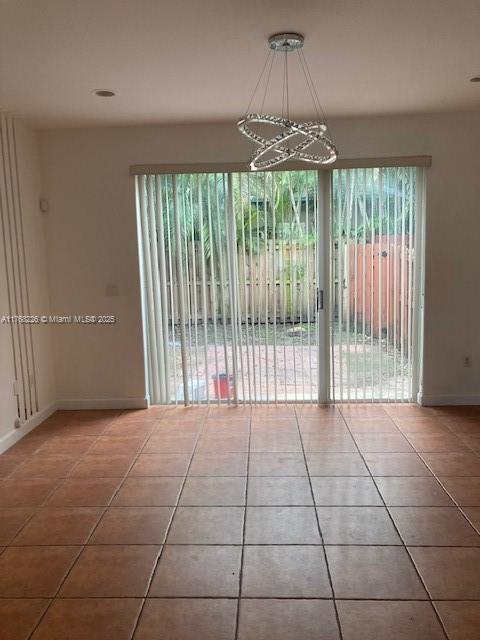 5450 NW 107th Ave Unit 705, Doral, FL 33178 - tiled empty room featuring an inviting chandelier and baseboards