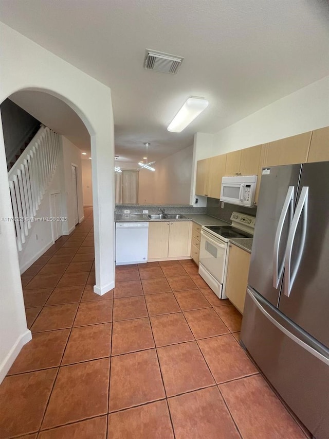 5450 NW 107th Ave Unit 705, Doral, FL 33178 - kitchen with white appliances, light tile patterned flooring, decorative backsplash, arched walkways, and cream cabinets