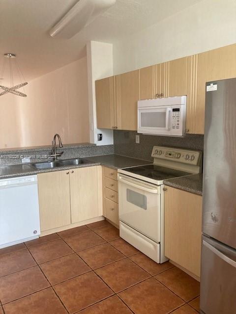 5450 NW 107th Ave Unit 705, Doral, FL 33178 - kitchen featuring white appliances, dark countertops, light brown cabinetry, and a sink