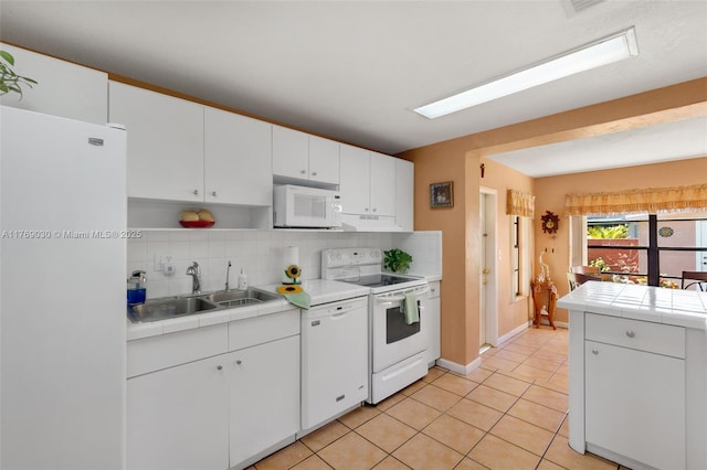 kitchen featuring a sink, white appliances, tasteful backsplash, and tile counters