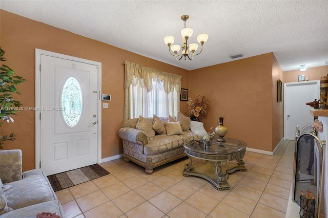 living area with visible vents, a notable chandelier, a textured ceiling, light tile patterned floors, and baseboards