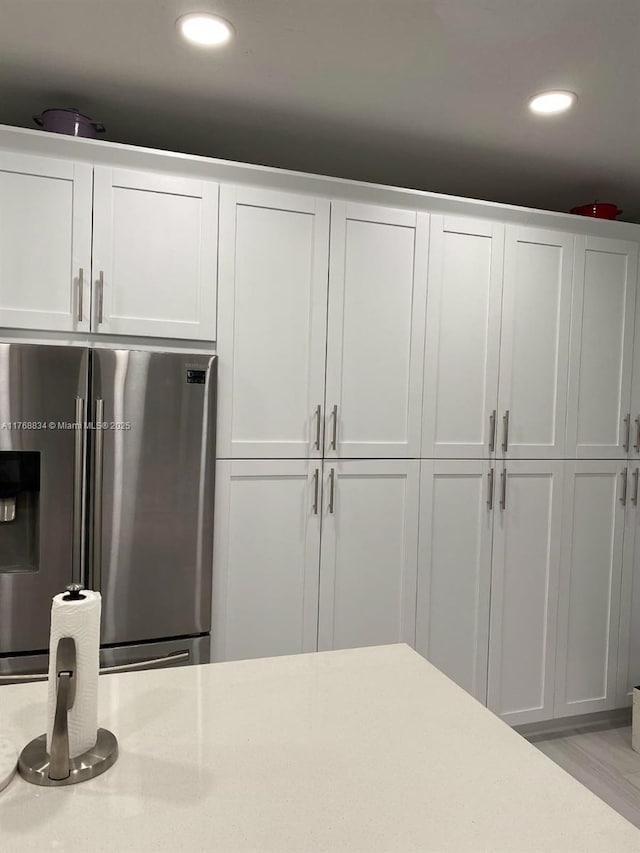 kitchen with recessed lighting, stainless steel fridge, white cabinetry, and light countertops